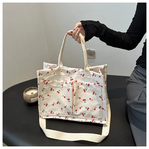 Détail du sac bandoulière en toile blanche à imprimé cerises et doubles poches