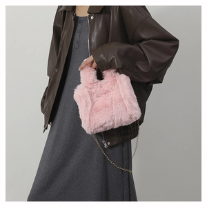 Detail of pink plush mini handbag with golden chain strap on a stylish model