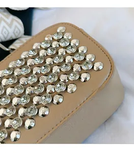 Detailed macro view of beige leather camera bag featuring shimmering silver rhinestones
