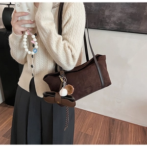Detail of dark brown faux suede shoulder bag with baseball charms on a female model