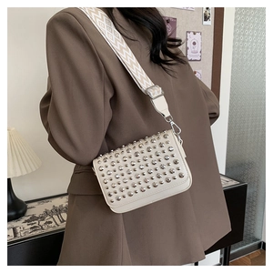 Close-up of off-white PU leather crossbody bag with silver studs and wide woven strap