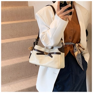 Detail of PU leather shoulder bag featuring a decorative bow and small bear charm