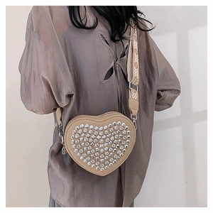 Gros plan sur un sac à bandoulière en PU beige en forme de cœur avec strass argentés