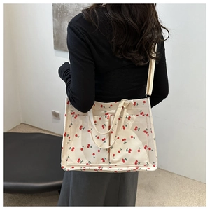 Détail du sac en toile imprimé cerises avec des poches frontales fonctionnelles