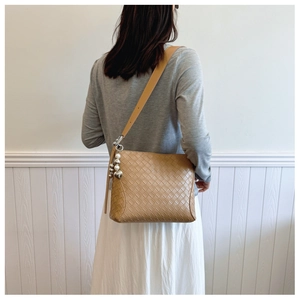 Detail of camel PU leather woven tote bag featuring decorative pearl and metal charms