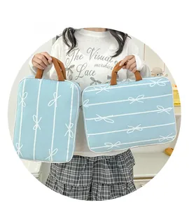 Detail view of light blue laptop bag with white bow patterns and brown handles
