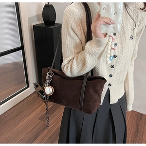Close-up of brown suede shoulder tote bag with a baseball charm on a lifestyle model