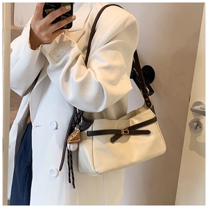 Close-up of cream PU leather shoulder bag with gold clasp and baseball charm detail