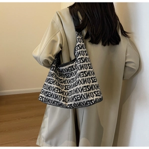 Detail view of large knit tote bag with black and white letter prints and leather piping