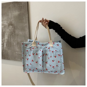 Détail du sac cabas en toile bleu clair avec motif cerise rouge et anses en tissage