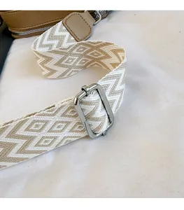 Close-up of beige geometric jacquard guitar strap with silver buckle and leather details