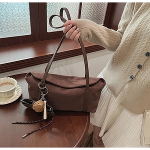 Close-up of brown suede shoulder bag with unique baseball glove and bat charms