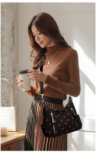 Detail of black corduroy crossbody bag with red strawberry pattern and wide strap