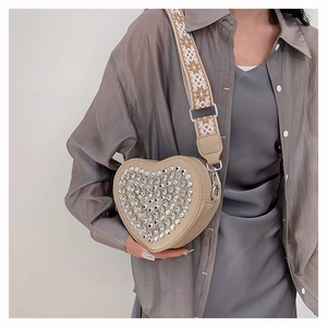 Détail d'un sac à bandoulière en similicuir beige en forme de cœur orné de strass brillants