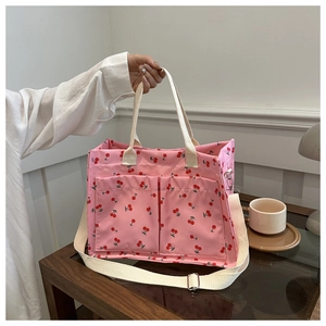 Détail du sac cabas rose à imprimé cerises avec poches avant et bandoulière crème