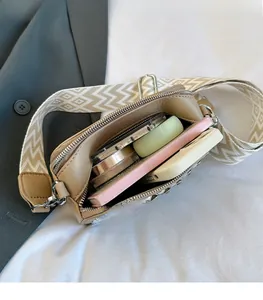 Brown leather camera bag with wide woven strap showing spacious interior for essentials