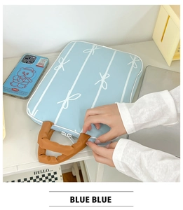 Close-up of light blue laptop sleeve with white bows and brown leather handles