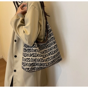 Detail of a large jacquard tote bag with SENXIN logo and dark brown leather straps