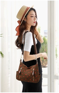 Detail of brown corduroy shoulder bag featuring red strawberry prints and leather straps