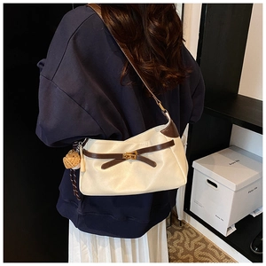 Detail view of the cream PU shoulder bag with brown bow trim and heart plush charm