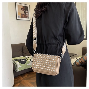 Detail of khaki PU shoulder bag with silver metallic studs and chevron strap on a model