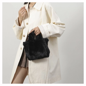 Close-up of soft black faux fur handbag with elegant gold metal chain shoulder strap