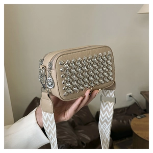 Detail of beige diamond square bag with silver rivets and chevron weave shoulder strap