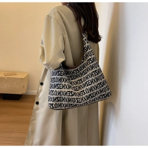 Detail of a large knit shoulder bag with black and white jacquard pattern and leather straps