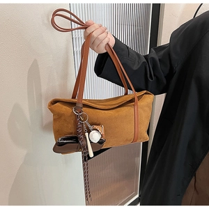 Detail of caramel suede tote bag featuring a creative baseball theme charm and leather strap