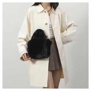 Detail of black faux fur plush shoulder bag with elegant gold metal chain strap
