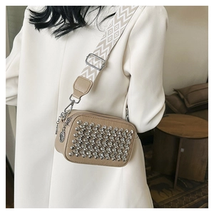 Detail of beige PU leather crossbody bag with silver studs and a woven geometric strap
