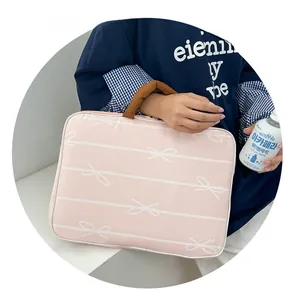 Detailed view of pink laptop sleeve with white bow patterns and brown handles