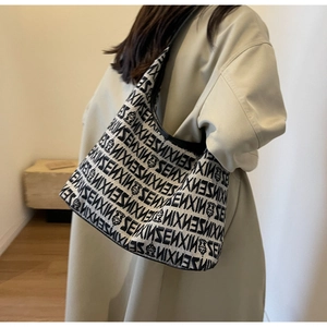 Detailed view of knitted shoulder bag featuring black SENXIN lettering pattern