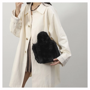 Close-up of fluffy black plush shoulder bag with fine gold chain strap on beige coat