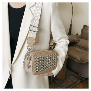 Detail view of stylish beige PU leather crossbody bag with silver studs and patterned strap