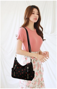 Close-up of black corduroy shoulder bag with red strawberry embroidery and gold hardware