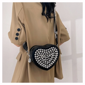 Détail du sac bandoulière en forme de cœur avec clous argentés et large bandoulière en nylon