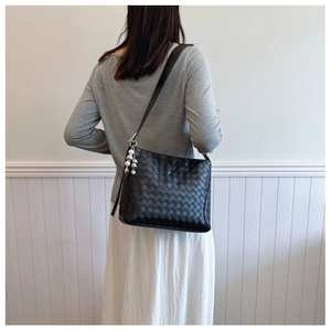Detail of black woven PU leather shoulder bag with pearl pendant and silver buckle