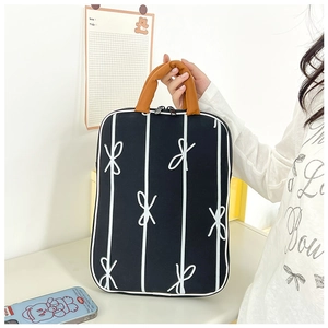 Detail of laptop sleeve with vertical white stripes, bow pattern and orange handles