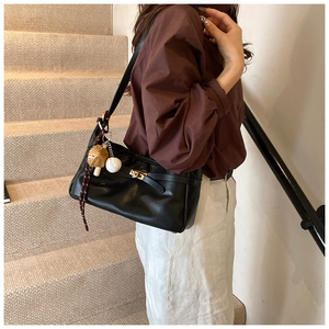 Close-up of black PU leather shoulder bag featuring a gold twist lock and cute bag charms