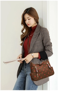 Close-up of brown corduroy shoulder bag with strawberry print and metal zipper detail