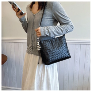 Detail view of black woven hobo bag with metallic heart charms on shoulder strap
