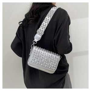Silver PU leather crossbody bag with metal rivets and wide woven strap on a model