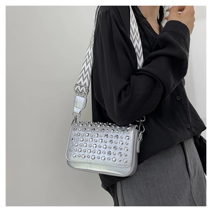 Detail of silver iridescent shoulder bag featuring studded flap and woven strap
