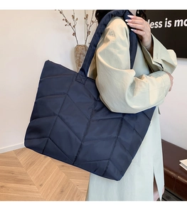 Detailed close-up of dark blue quilted nylon tote bag showing geometric stitching