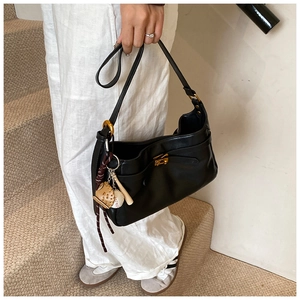 Detail of black PU leather tote bag with golden metal twist lock and baseball glove charm