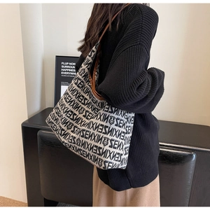 Detail of knit tote bag featuring black bear jacquard pattern and leather strap