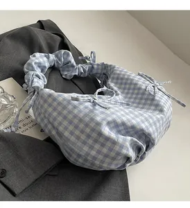Close-up of blue and white checkered fabric handbag with stylish ruffled handle details