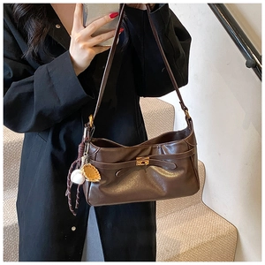 Detail view of coffee PU leather shoulder bag with gold twist lock and baseball charm