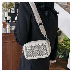 Detail of white PU leather crossbody bag with silver punk studs and geometric strap